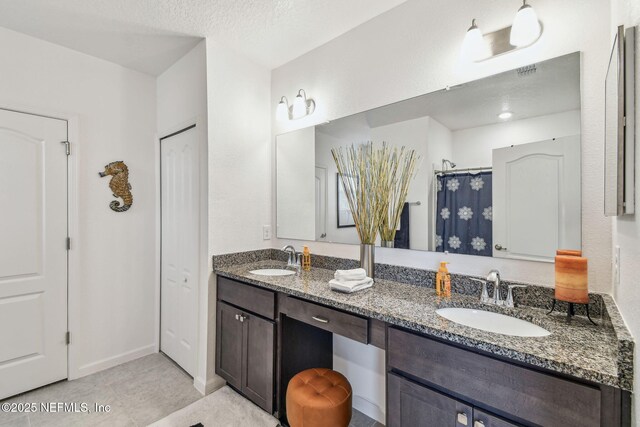 bathroom with tile patterned flooring, vanity, curtained shower, and a textured ceiling