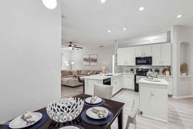 kitchen with white cabinetry, black appliances, kitchen peninsula, and a center island