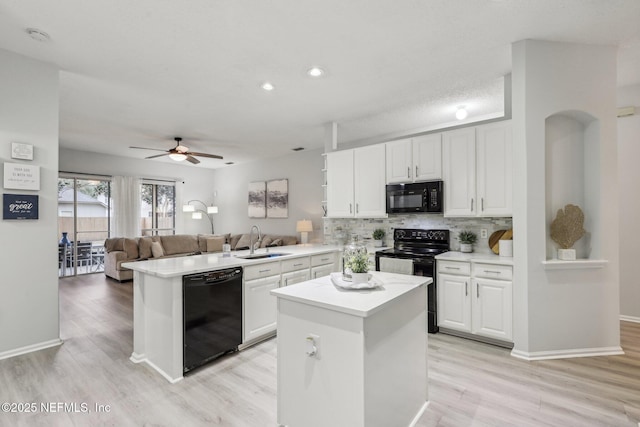 kitchen featuring white cabinetry, sink, a kitchen island, and black appliances