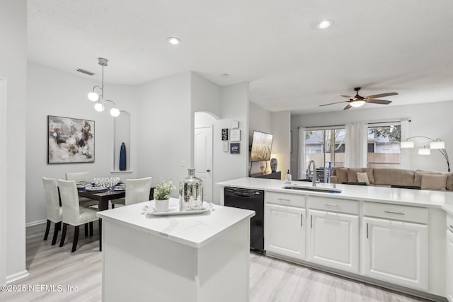 kitchen featuring sink, white cabinetry, hanging light fixtures, black dishwasher, and light wood-type flooring