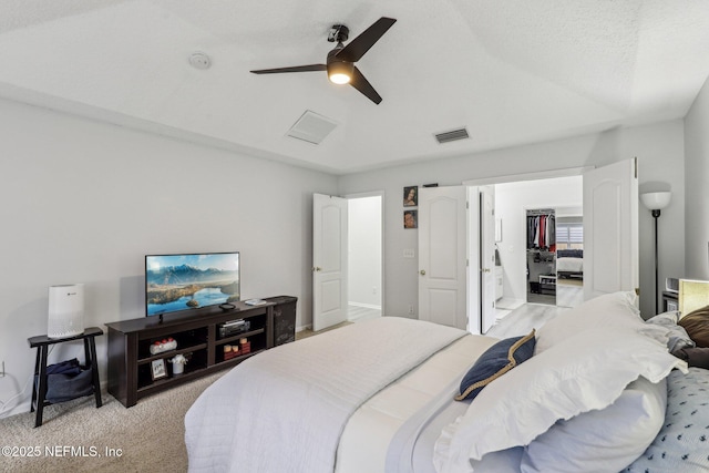 bedroom featuring light carpet, a walk in closet, and ceiling fan