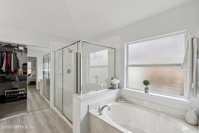 bathroom with hardwood / wood-style flooring, shower with separate bathtub, vaulted ceiling, and a textured ceiling