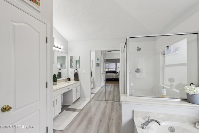 bathroom with lofted ceiling, shower with separate bathtub, a textured ceiling, vanity, and hardwood / wood-style flooring