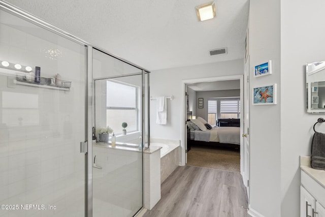 bathroom featuring hardwood / wood-style flooring, vanity, shower with separate bathtub, and a textured ceiling