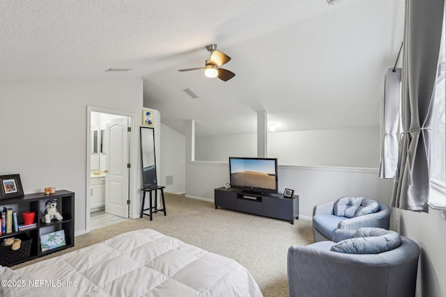 carpeted bedroom featuring ceiling fan, ensuite bath, vaulted ceiling, and a textured ceiling