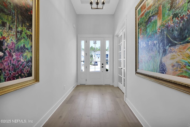 doorway featuring a notable chandelier and light hardwood / wood-style flooring