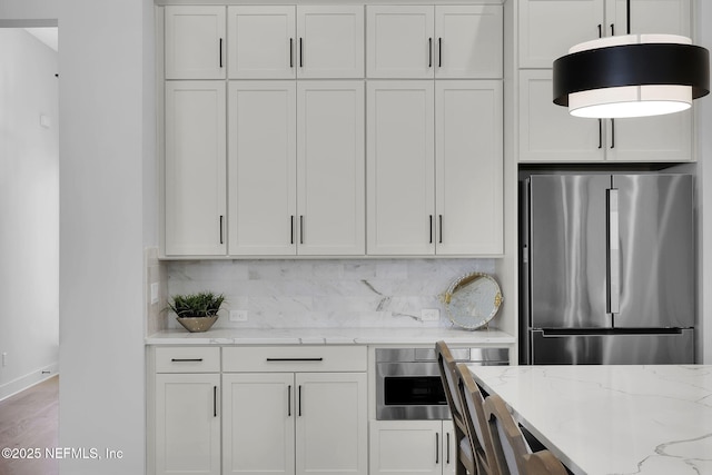 kitchen with white cabinetry, light stone countertops, and stainless steel fridge