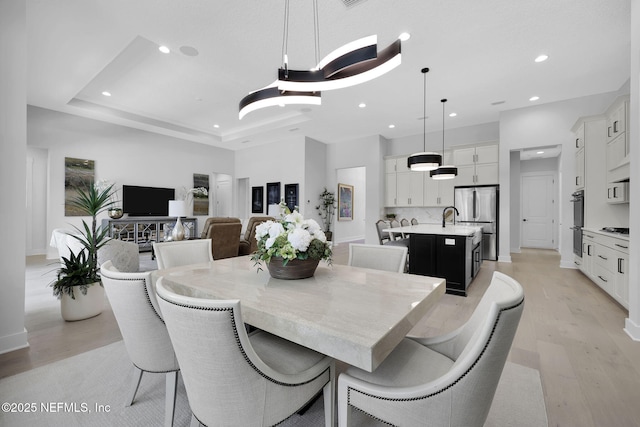 dining room with light hardwood / wood-style flooring and a tray ceiling