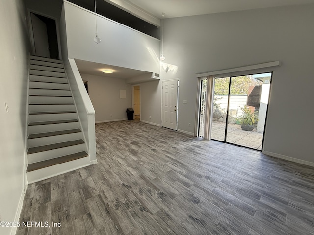 unfurnished living room featuring hardwood / wood-style flooring and a towering ceiling