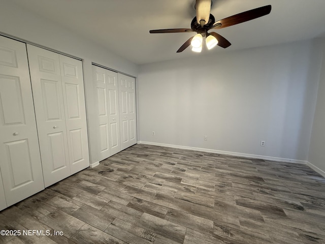 unfurnished bedroom with two closets, ceiling fan, and light wood-type flooring