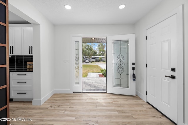 entryway with a textured ceiling and light hardwood / wood-style floors