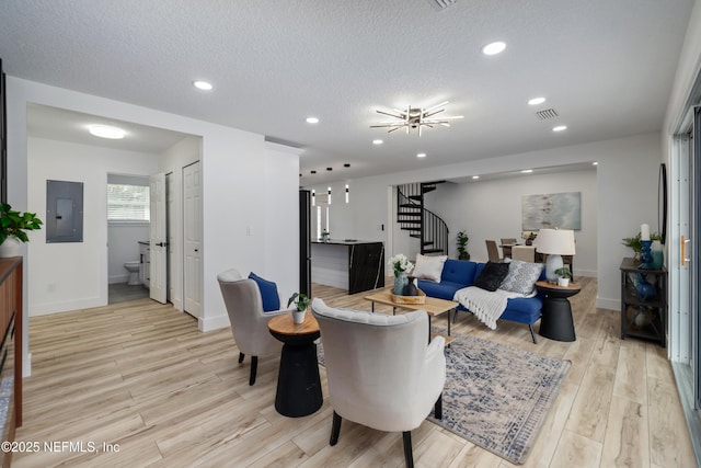 living room featuring a textured ceiling, electric panel, and light wood-type flooring