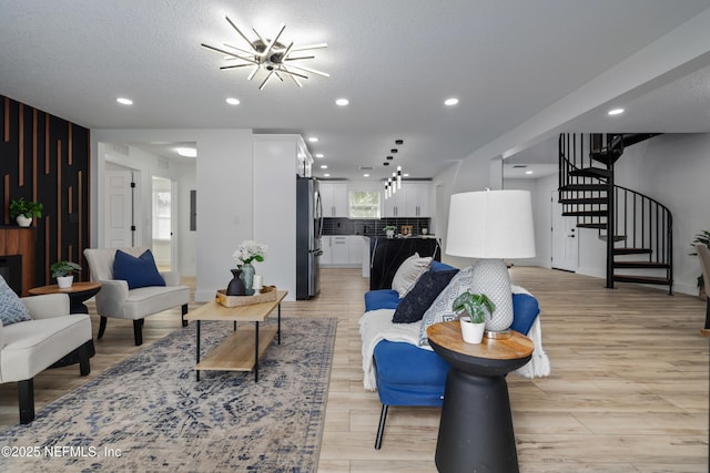 living room featuring an inviting chandelier, a textured ceiling, and light hardwood / wood-style floors