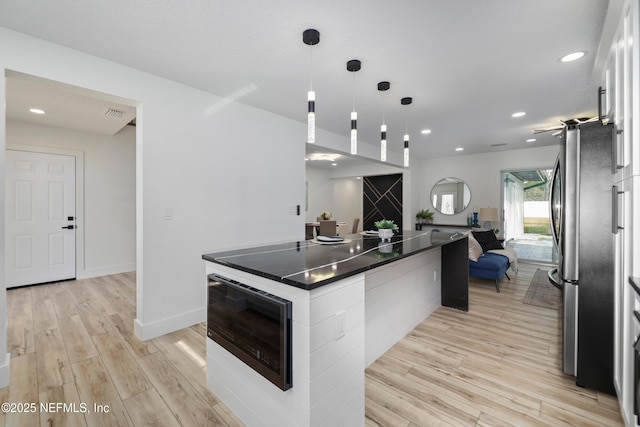 kitchen featuring pendant lighting, white cabinetry, stainless steel fridge, and light wood-type flooring