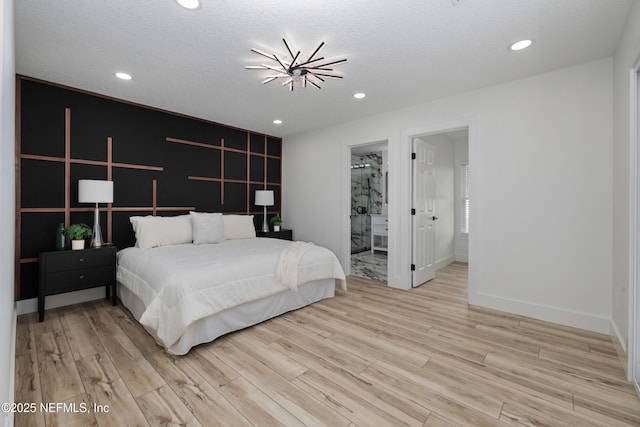 bedroom featuring connected bathroom, light hardwood / wood-style flooring, and a textured ceiling