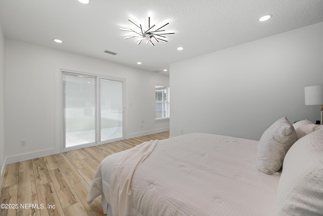 bedroom featuring a notable chandelier, access to outside, and light hardwood / wood-style floors