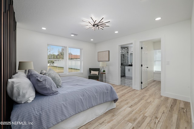 bedroom with ensuite bathroom and light hardwood / wood-style floors