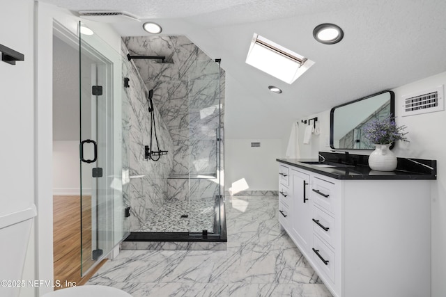 bathroom with vanity, lofted ceiling with skylight, a textured ceiling, and walk in shower