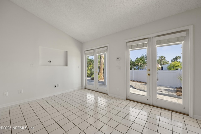 tiled empty room featuring lofted ceiling, french doors, and a textured ceiling