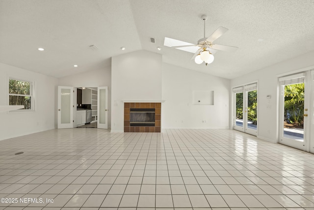 unfurnished living room featuring a tiled fireplace, light tile patterned floors, a wealth of natural light, and a skylight