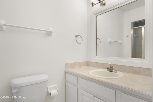 bathroom featuring vanity, an enclosed shower, and toilet