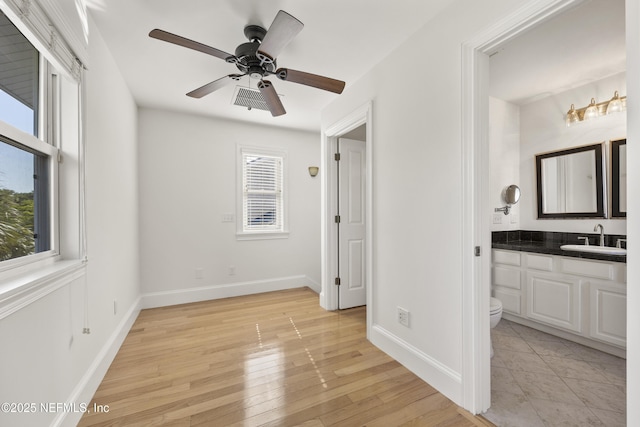 bedroom with ensuite bathroom, light hardwood / wood-style floors, and sink