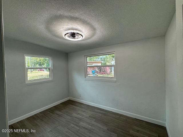 spare room featuring dark hardwood / wood-style flooring and a textured ceiling