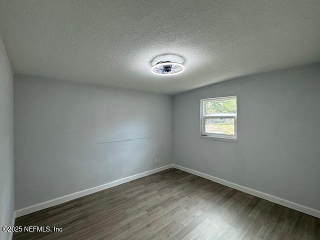 spare room with dark wood-type flooring and a textured ceiling