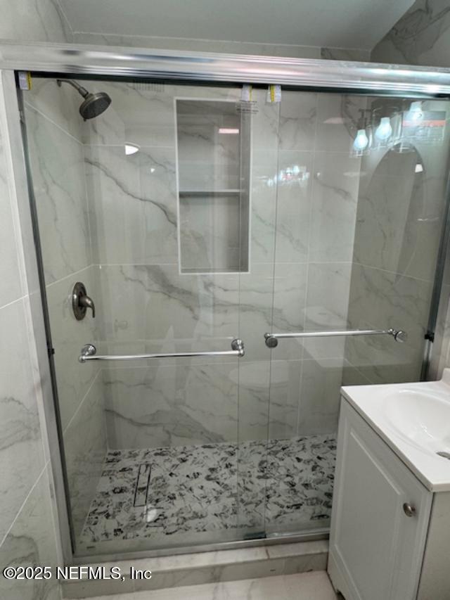 bathroom featuring vanity and a shower with door