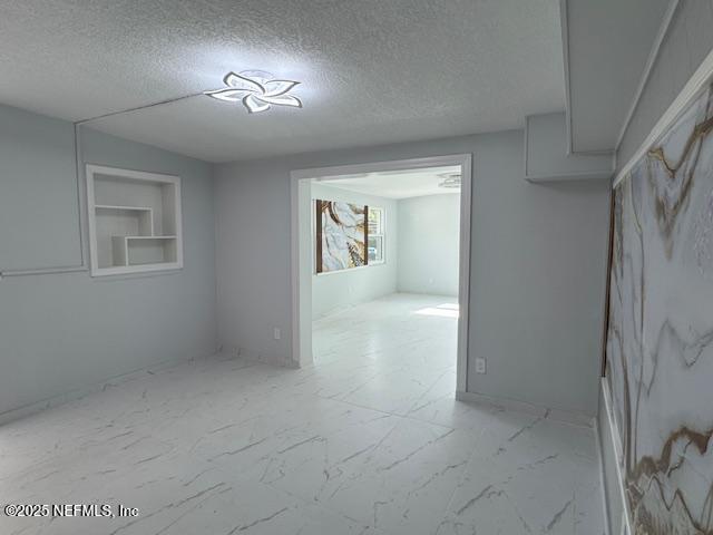 unfurnished room featuring built in features and a textured ceiling