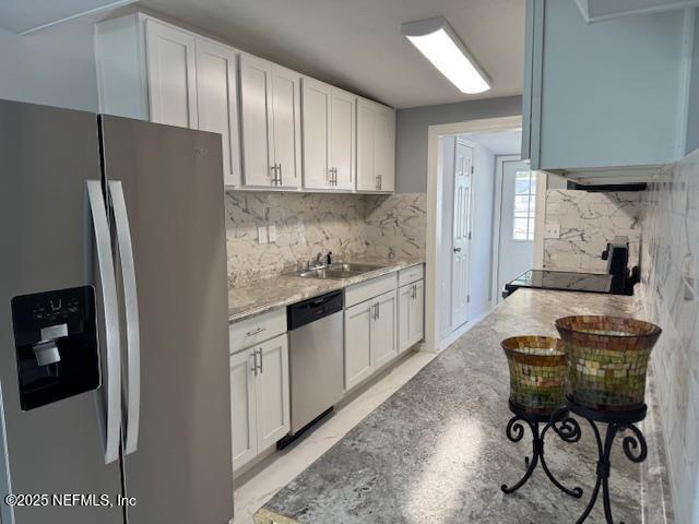 kitchen with light stone counters, sink, white cabinets, and appliances with stainless steel finishes