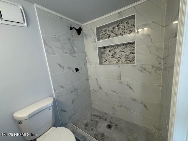 bathroom featuring a tile shower and toilet