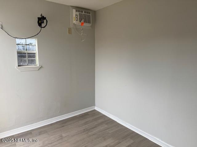 unfurnished room featuring dark hardwood / wood-style floors and a wall unit AC