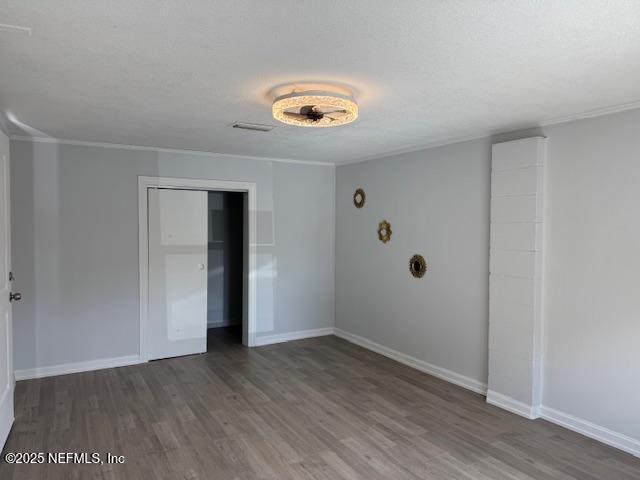 unfurnished bedroom featuring crown molding, dark wood-type flooring, a textured ceiling, and a closet