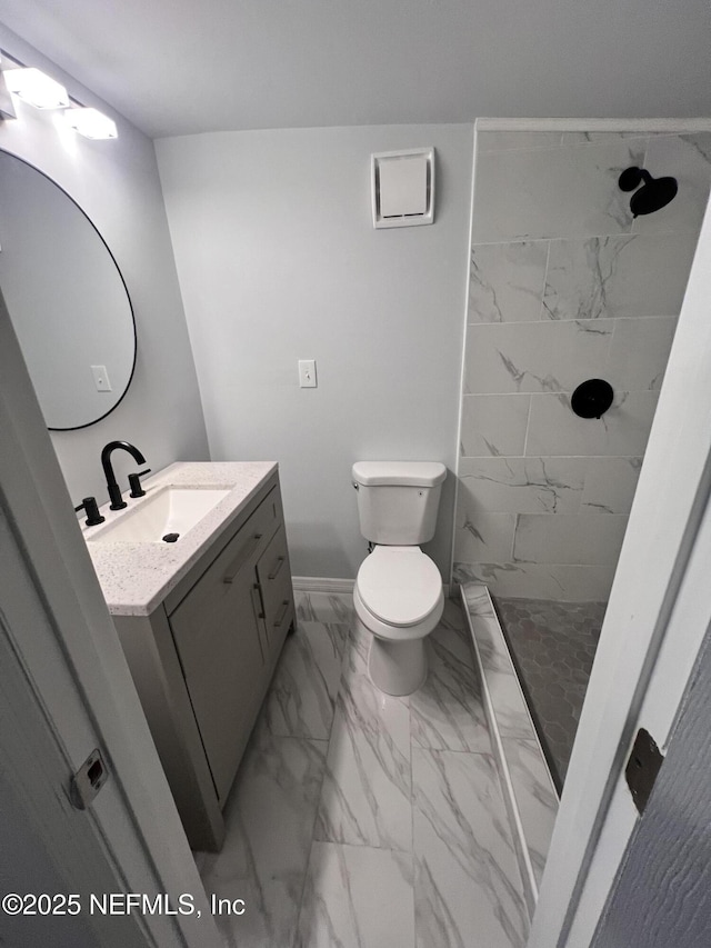 bathroom with tiled shower, vanity, and toilet