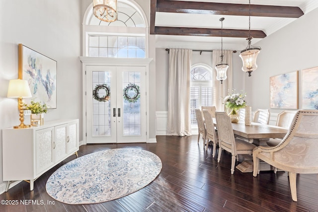 entryway featuring french doors, a chandelier, dark hardwood / wood-style floors, a towering ceiling, and beam ceiling