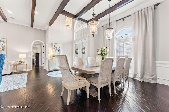 dining room featuring dark hardwood / wood-style flooring, a notable chandelier, a towering ceiling, and beamed ceiling