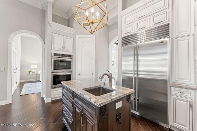 kitchen with sink, crown molding, dark wood-type flooring, stainless steel appliances, and dark brown cabinetry