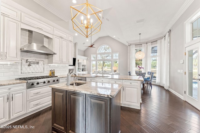 kitchen featuring pendant lighting, stainless steel gas stovetop, wall chimney exhaust hood, and a center island with sink