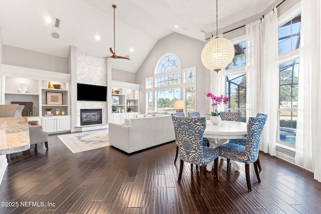 dining room with built in shelves, a fireplace, high vaulted ceiling, and dark hardwood / wood-style floors