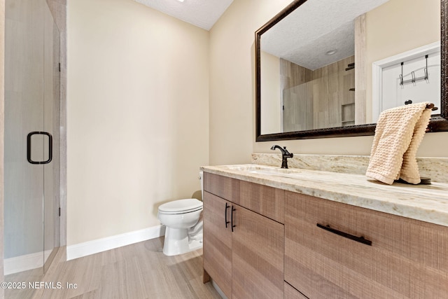 bathroom with walk in shower, vanity, toilet, and a textured ceiling