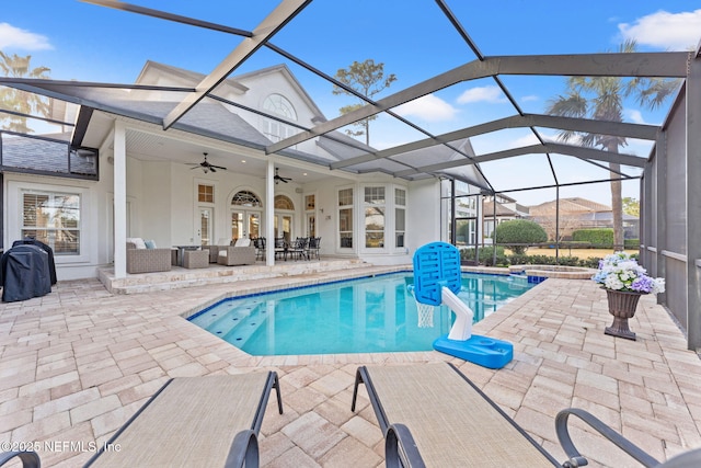 view of swimming pool with ceiling fan, outdoor lounge area, glass enclosure, a patio area, and an in ground hot tub