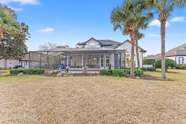 rear view of property featuring a pool, a lawn, ceiling fan, and glass enclosure