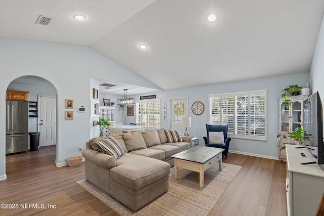 living room featuring wood-type flooring, vaulted ceiling, and a textured ceiling