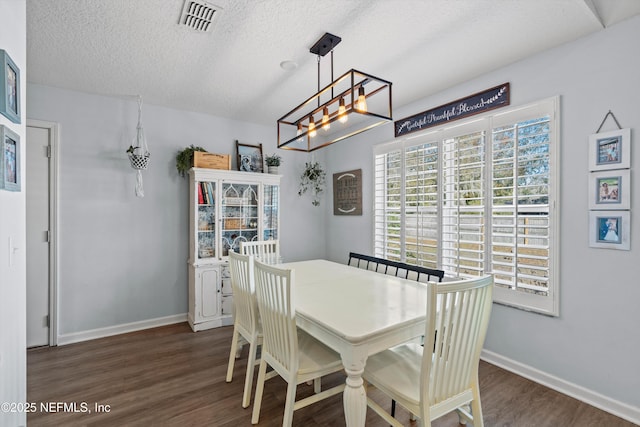 dining room with dark wood-type flooring and a textured ceiling