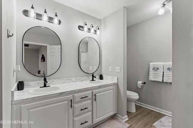 bathroom with vanity, toilet, hardwood / wood-style floors, and a textured ceiling