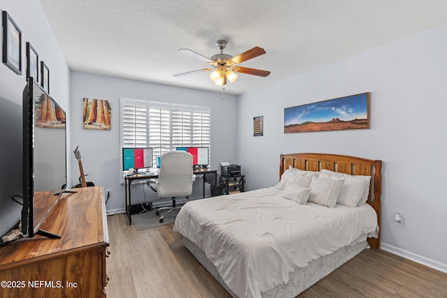 bedroom with ceiling fan, wood-type flooring, and a textured ceiling