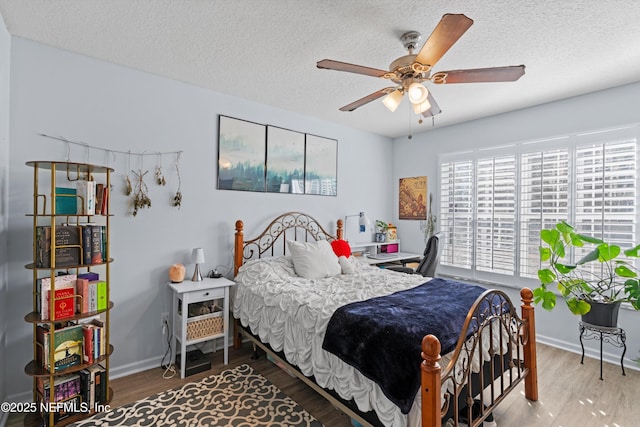 bedroom featuring ceiling fan, wood-type flooring, and a textured ceiling