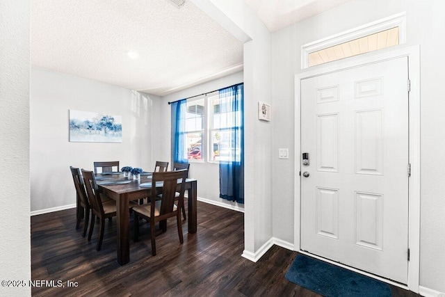 dining area featuring dark wood-type flooring and a textured ceiling