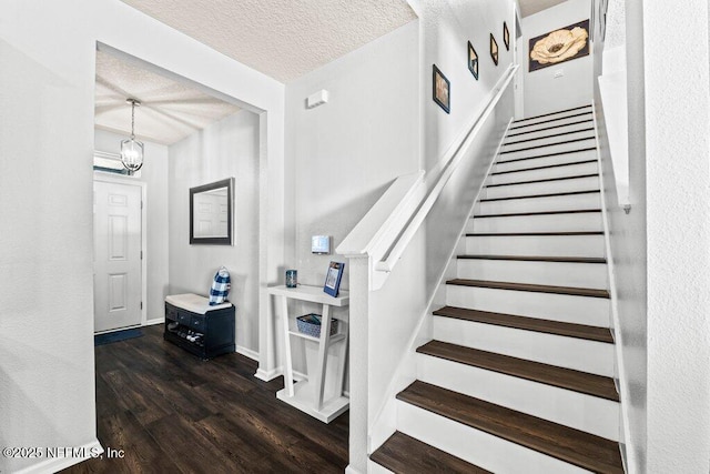 staircase with hardwood / wood-style flooring, an inviting chandelier, and a textured ceiling